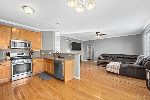 kitchen featuring sink, ornamental molding, pendant lighting, backsplash, and stainless steel appliances