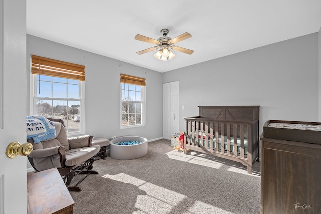 bedroom featuring ceiling fan, a nursery area, and carpet floors