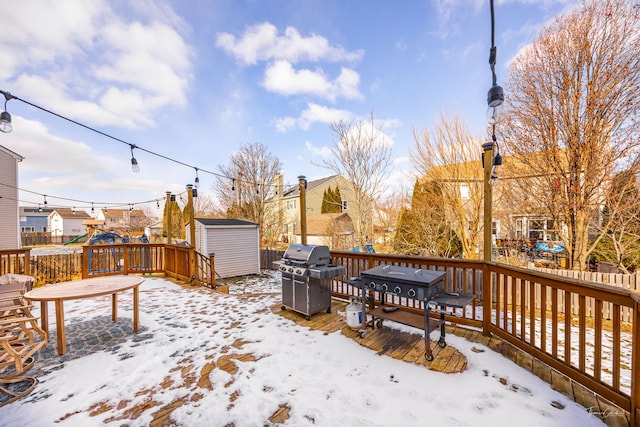 snow covered deck with a shed and grilling area