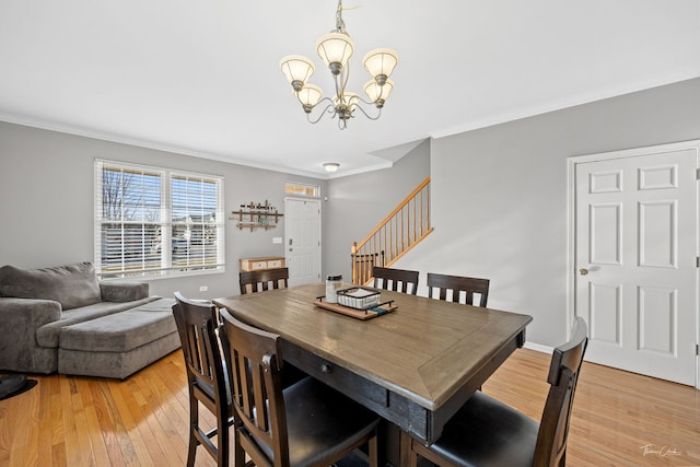 dining area featuring light wood-type flooring, an inviting chandelier, and ornamental molding