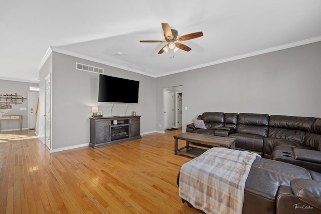 living room with a fireplace, light hardwood / wood-style flooring, ceiling fan, and ornamental molding