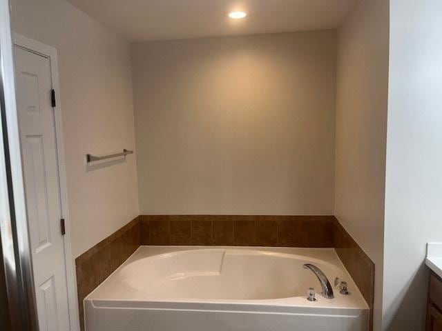 bathroom with a tub to relax in and vanity