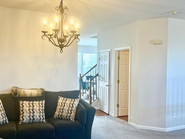 carpeted living room featuring a chandelier