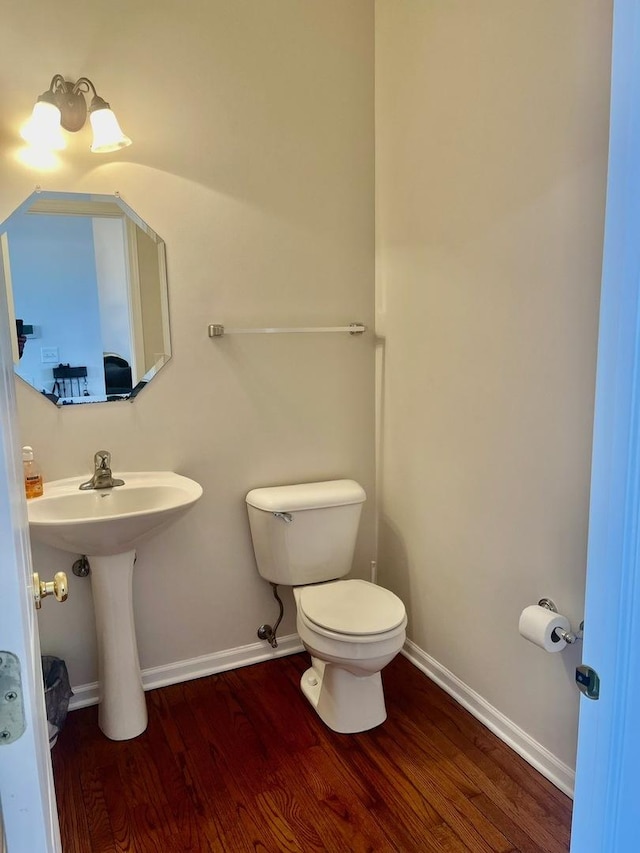 bathroom with toilet, wood-type flooring, and sink