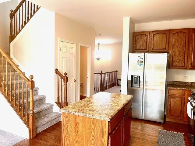 kitchen with stove, a kitchen island, dark hardwood / wood-style flooring, and stainless steel fridge