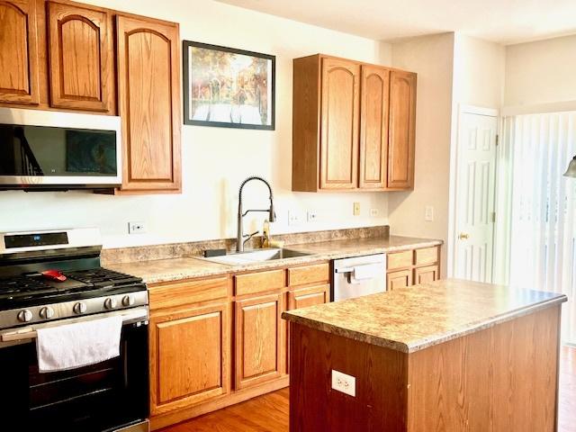 kitchen featuring light wood-type flooring, appliances with stainless steel finishes, a center island, and sink