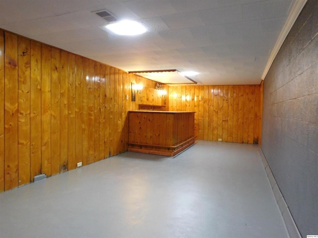 basement featuring bar area and wood walls