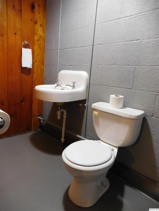 bathroom featuring sink, concrete flooring, and toilet