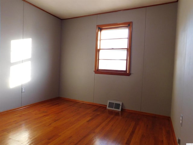 spare room featuring hardwood / wood-style flooring and ornamental molding