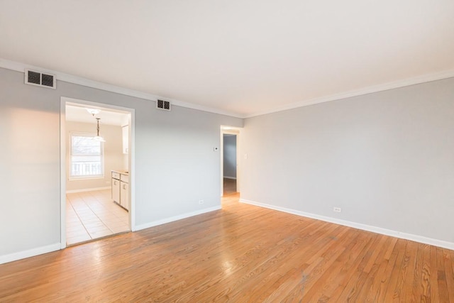 empty room featuring crown molding and light wood-type flooring