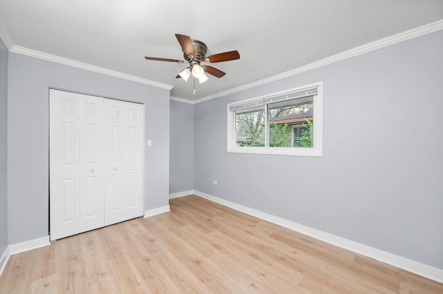 unfurnished bedroom with a closet, ornamental molding, ceiling fan, light wood finished floors, and baseboards