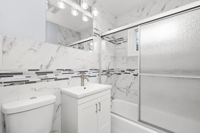 bathroom with toilet, enclosed tub / shower combo, vanity, and tile walls