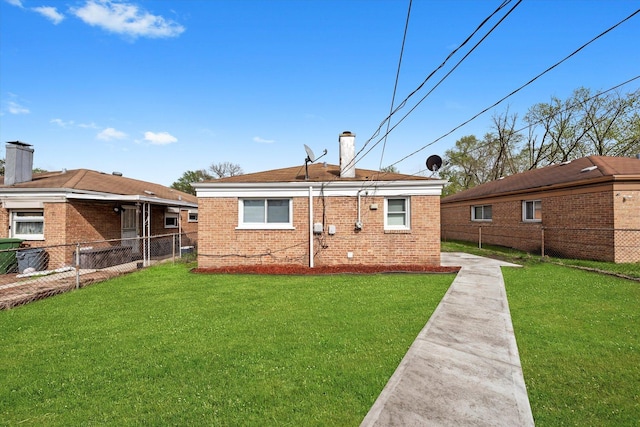 back of property with fence, a chimney, a yard, and brick siding