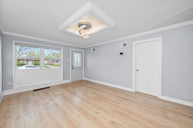empty room with baseboards, visible vents, ornamental molding, and light wood-type flooring