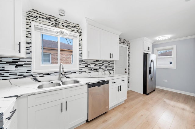 kitchen featuring a sink, stainless steel appliances, tasteful backsplash, light wood-style flooring, and white cabinets