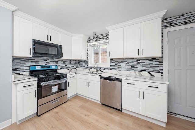 kitchen with backsplash, a sink, white cabinets, and appliances with stainless steel finishes