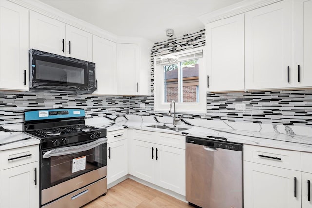 kitchen featuring decorative backsplash, white cabinets, a sink, stainless steel appliances, and light stone countertops