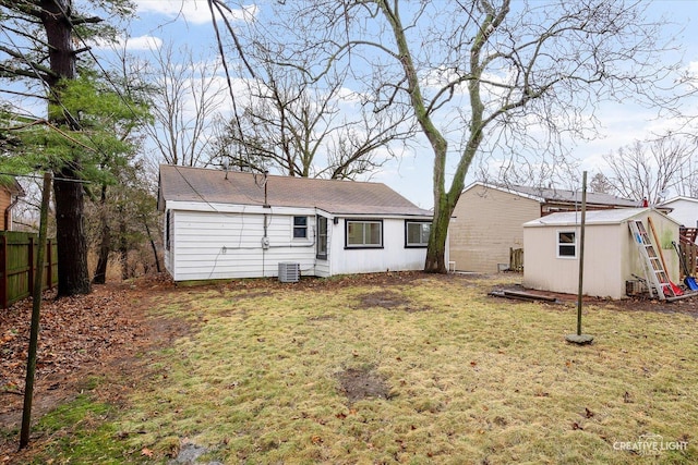 rear view of property featuring a lawn, central AC unit, and a shed