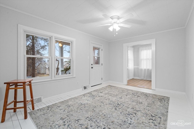 tiled entryway with ornamental molding and ceiling fan