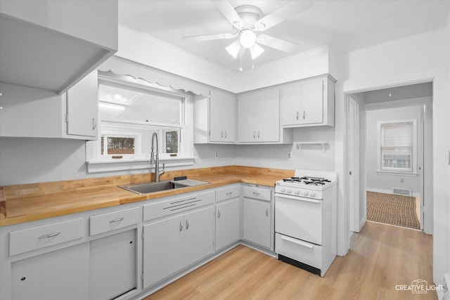 kitchen featuring butcher block counters, sink, ceiling fan, white gas stove, and light hardwood / wood-style flooring