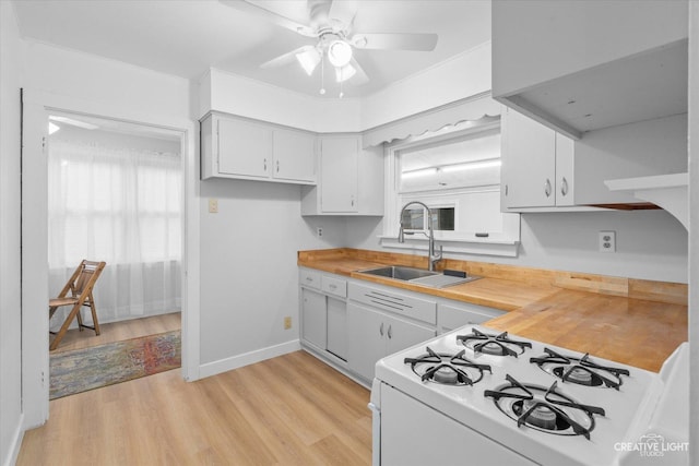 kitchen featuring sink, butcher block countertops, light hardwood / wood-style flooring, white cabinetry, and white range with gas cooktop