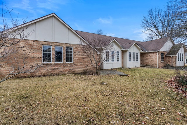 rear view of property featuring a lawn and brick siding