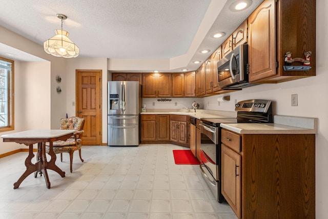 kitchen featuring appliances with stainless steel finishes, brown cabinets, decorative light fixtures, light countertops, and light floors