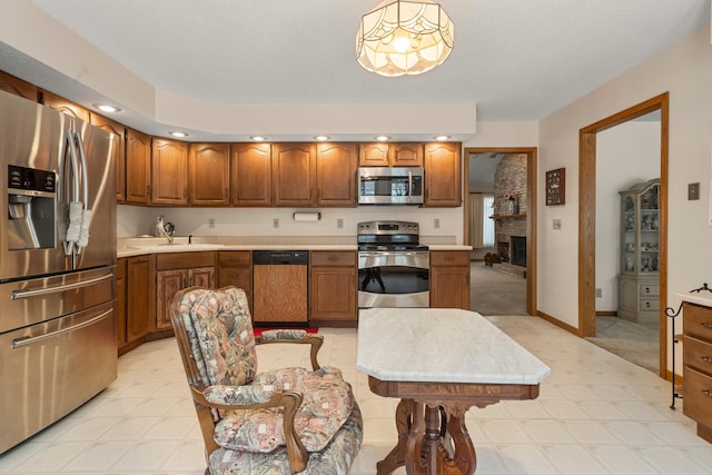 kitchen featuring stainless steel appliances, a fireplace, and hanging light fixtures