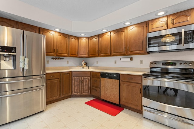 kitchen featuring brown cabinets, light floors, stainless steel appliances, and light countertops