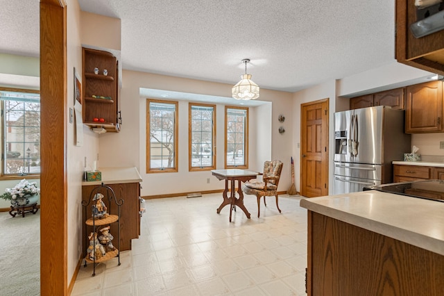 kitchen featuring pendant lighting, stainless steel fridge, and a textured ceiling