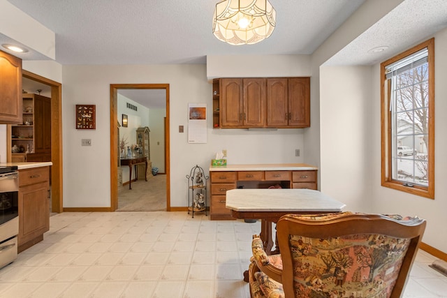 kitchen with brown cabinets, visible vents, open shelves, and light countertops