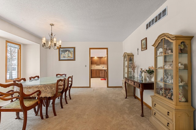 dining room with light carpet, a chandelier, and a textured ceiling