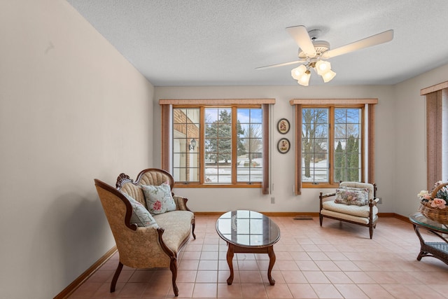 living area featuring light tile patterned floors, a textured ceiling, a wealth of natural light, and ceiling fan