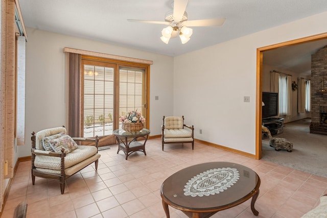 living area with baseboards, light tile patterned flooring, a ceiling fan, and light colored carpet