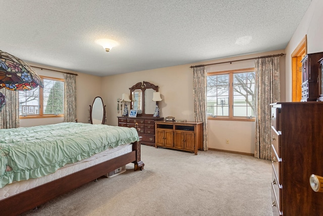 bedroom featuring light carpet, a textured ceiling, and baseboards