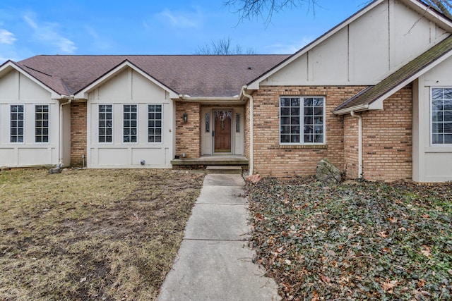 view of front of property featuring roof with shingles, a front lawn, and brick siding