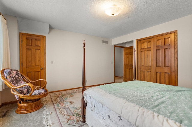 carpeted bedroom with baseboards, a textured ceiling, visible vents, and a closet