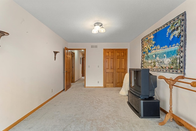 interior space with carpet, visible vents, a textured ceiling, and baseboards