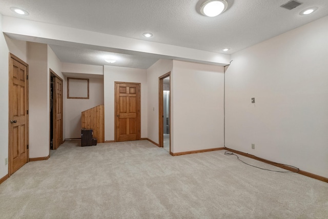 spare room featuring light carpet, baseboards, visible vents, a textured ceiling, and recessed lighting