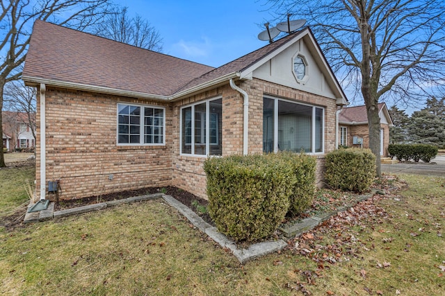 view of property exterior with a yard, roof with shingles, and brick siding