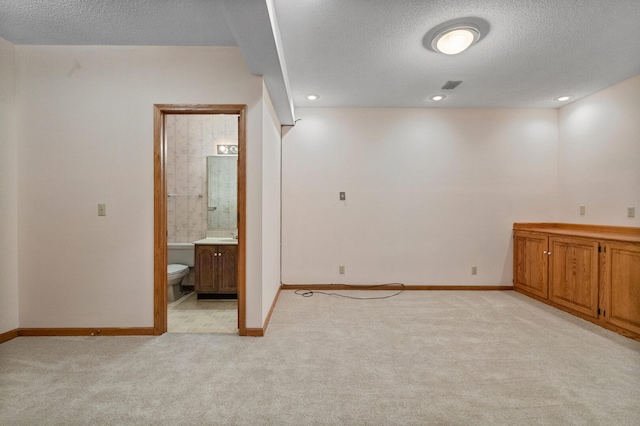 interior space with baseboards, a textured ceiling, and light colored carpet