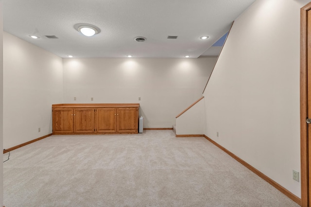 below grade area with light carpet, recessed lighting, visible vents, and baseboards