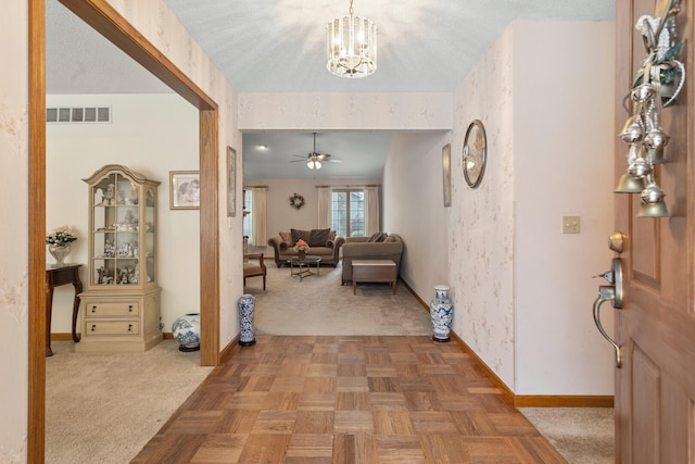 entrance foyer with a notable chandelier, light colored carpet, visible vents, baseboards, and wallpapered walls