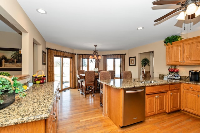 kitchen featuring light wood-type flooring, hanging light fixtures, light stone countertops, and sink