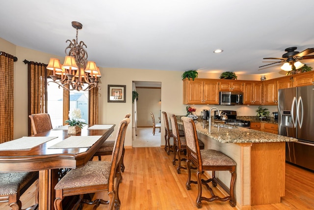 interior space featuring hanging light fixtures, sink, stone counters, light hardwood / wood-style floors, and stainless steel appliances