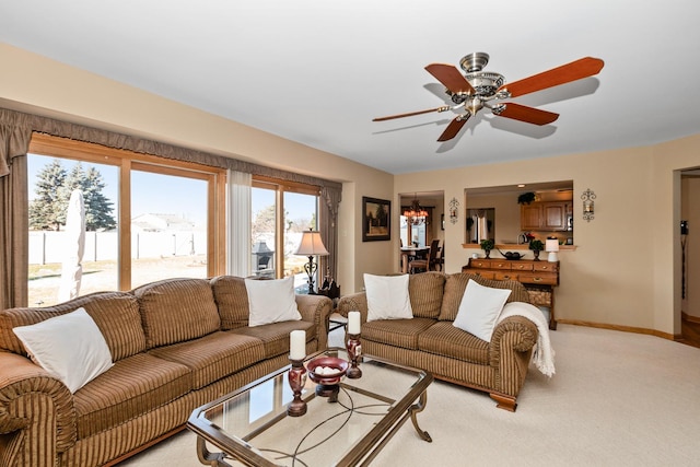 carpeted living room featuring ceiling fan with notable chandelier