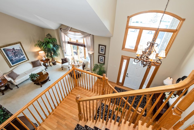 foyer featuring a healthy amount of sunlight, hardwood / wood-style flooring, a high ceiling, and a notable chandelier