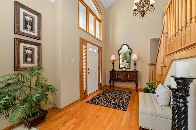 foyer with hardwood / wood-style flooring, a towering ceiling, and an inviting chandelier