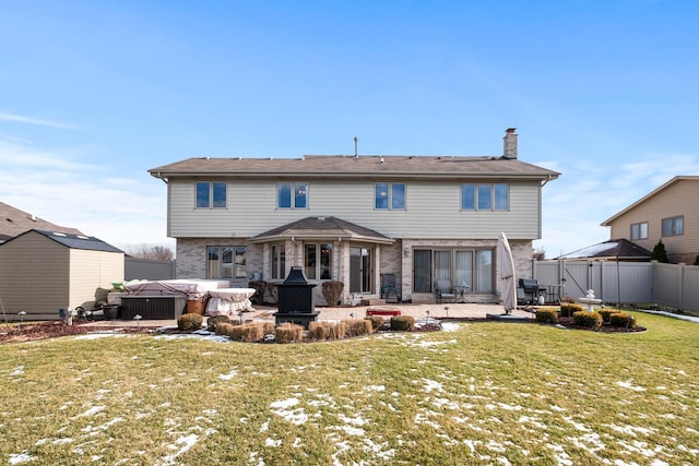 back of house featuring a hot tub, a lawn, and a patio