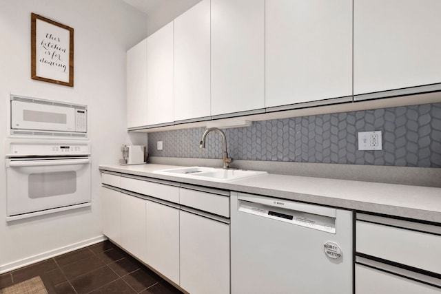 kitchen featuring white cabinetry, tasteful backsplash, white appliances, dark tile patterned flooring, and sink